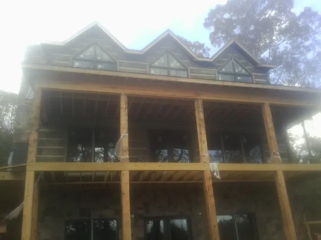 Dormers and porch framing on a large log home under construction — Roof Coating work by our crew in Bloomington