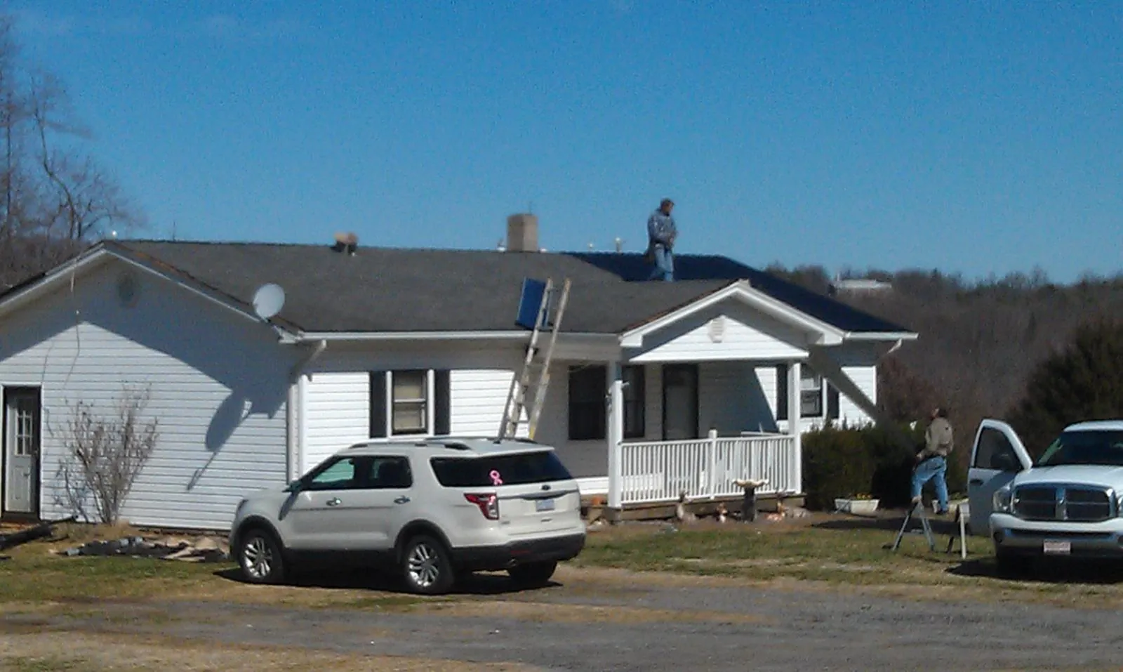 Roofers stripping shingles from a white ranch house roof in Bloomington